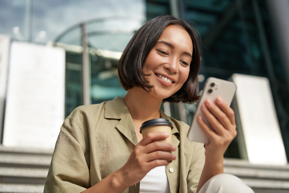 Woman sitting on stairs looking at phone outside
